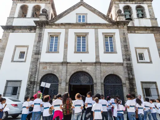 Alunos do CIEP Francisco Cavalcanti Pontes de Miranda em frente à igreja, com o caderno de atividades.